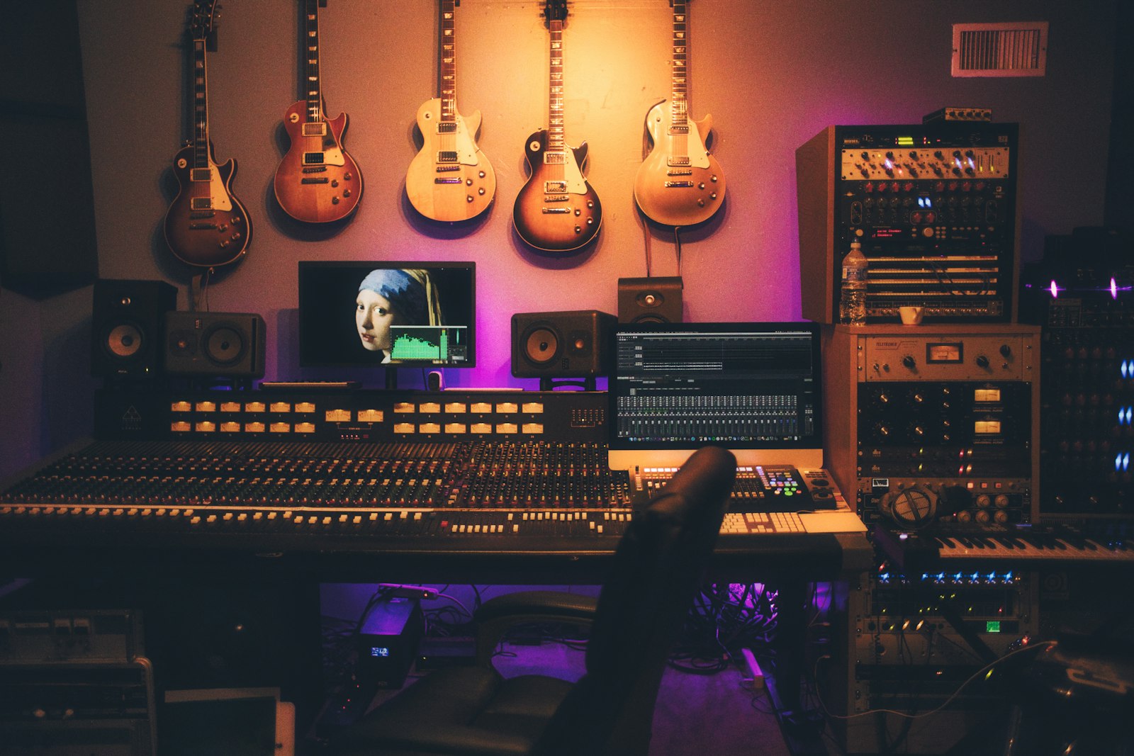 A mixing desk, monitors, and guitars in a studio